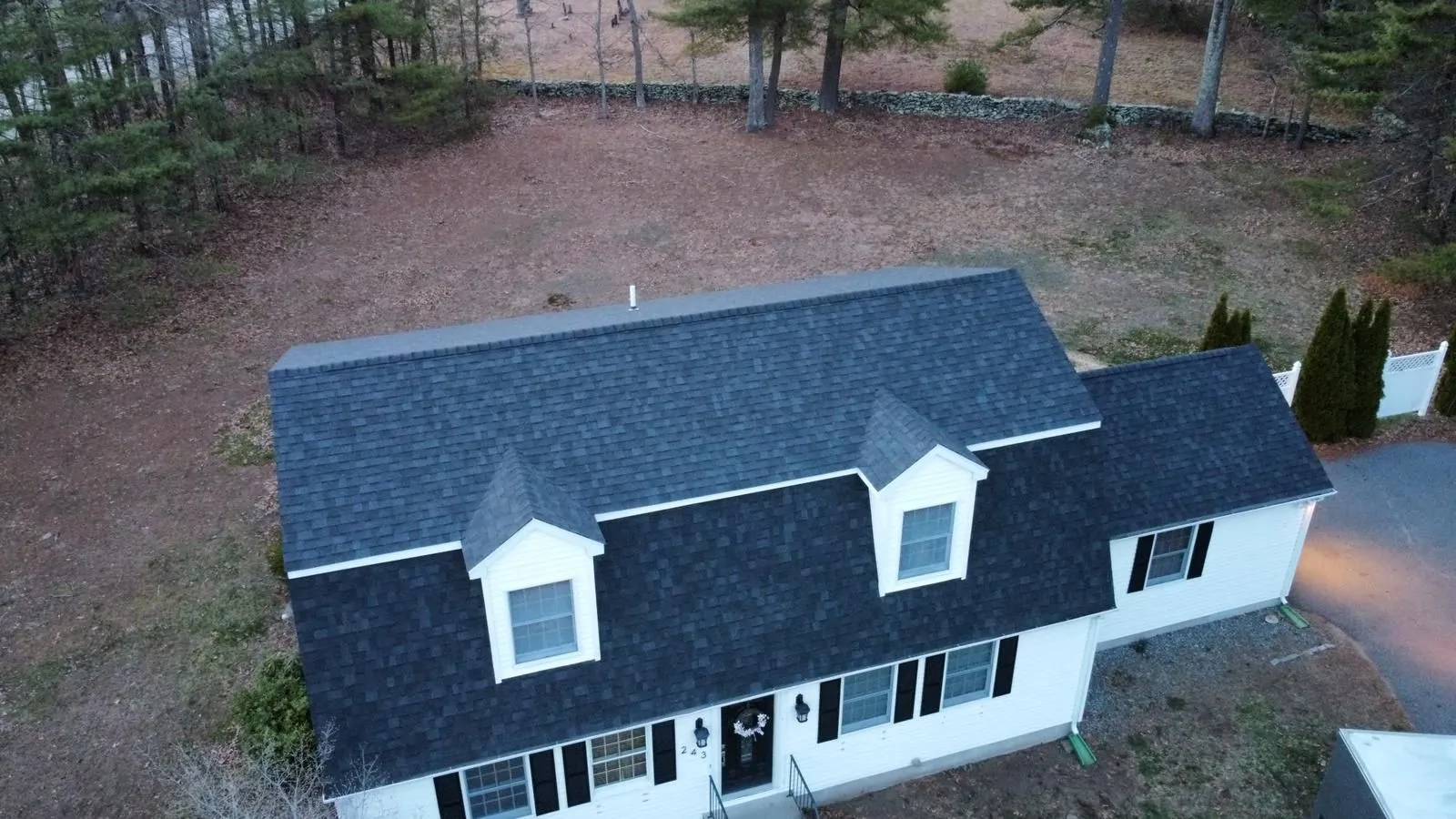 Aerial view of a white home with a new asphalt shingle roof installed by Hammerhead Roofing